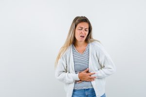 young lady in t-shirt, jacket suffering from stomach pain and l