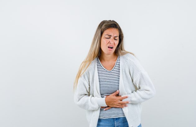 young lady in t-shirt, jacket suffering from stomach pain and l