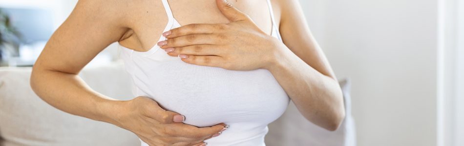 Young caucasian woman palpating her breast by herself that she concern about breast cancer. Healthcare and breast cancer concept