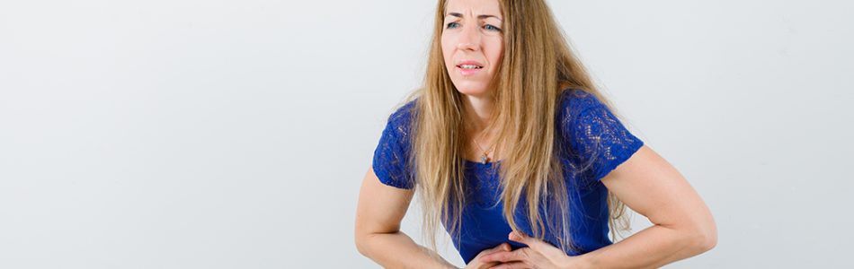 Portrait of blonde lady suffering from stomachache in blue blouse and looking painful front view