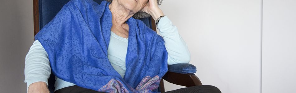 Pensive senior lady sitting in rocking chair and looking away. Calm old woman with curly hair relaxing at home. Contemplation concept